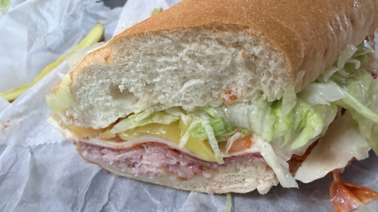 Close-up of the cut end of the Little Italy, showing layered salami, cheese, banana pepper, tomato and shredded lettuce